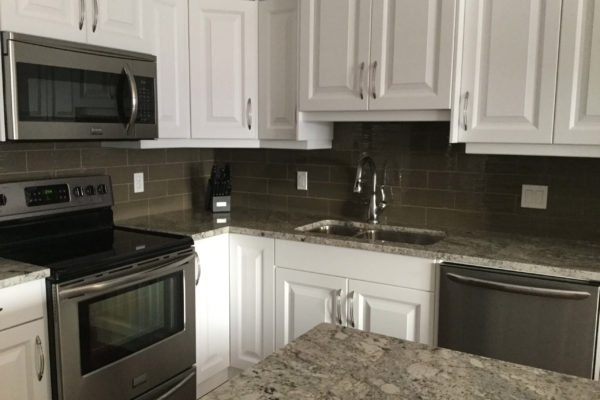 Kitchen with white cabinets and grey backsplash
