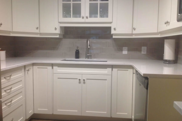 Kitchen with white cupboards and grey subway tile style backsplash