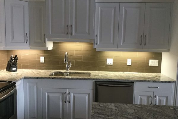 Kitchen with backsplash lit by lighting under cabinets.